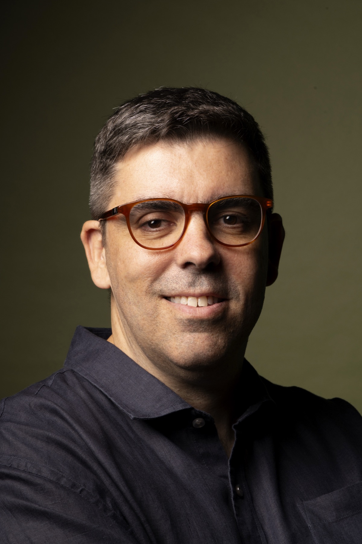 Close de Eduardo Cruz sorrindo, de óculos âmbar